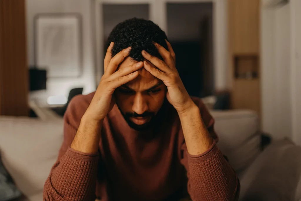 A worried man with his head in his hands, a sign of eco-anxiety