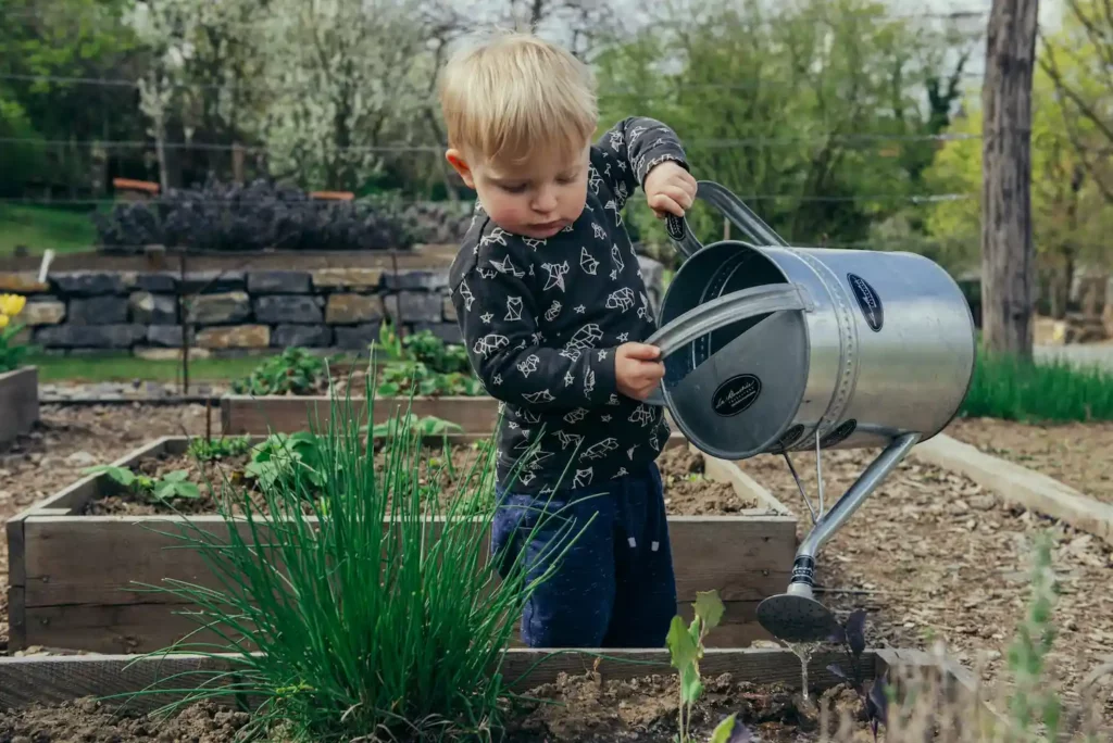 Little boy watering a garden: reconnecting with nature against eco-anxiety